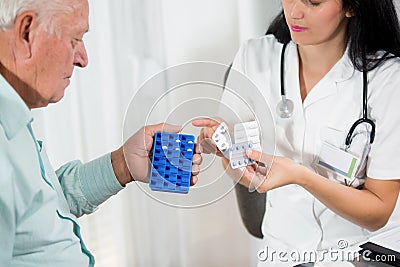 Doctor shows the patient how to use daily dose pills Stock Photo