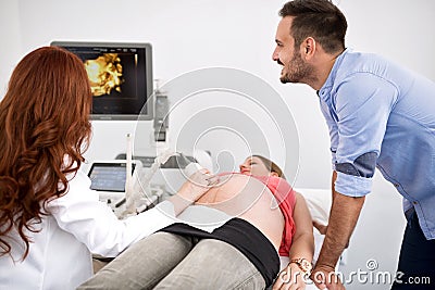 Doctor shows an ultrasound to a young happy couple Stock Photo