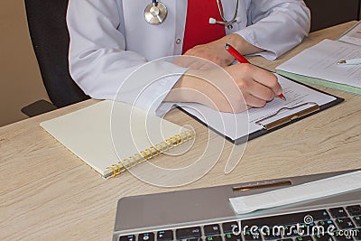 Doctor sits in a medical office in the clinic and writes medical history. Medicine doctor`s working table Stock Photo