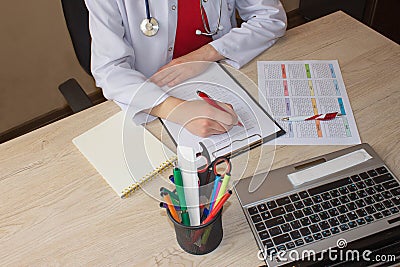 Doctor sits in a medical office in the clinic and writes medical history. Medicine doctor`s working table Stock Photo