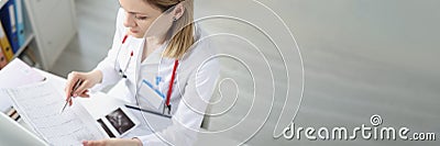 Doctor sitting at table and looking at cardiogram in clinic Stock Photo