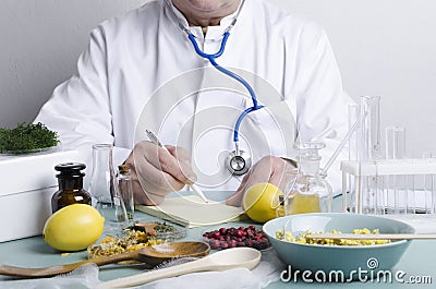 Doctor sitting at the table. Many ingredients for alternative medicine.Dried berries,herbs,lemons and diffirent portions of natura Stock Photo