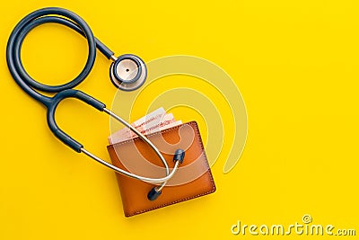 Doctor stethoscope and the new leather brown men wallet on yellow background. Budget for health check or money and financial Stock Photo