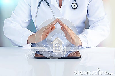 Doctor at the table with his hands to protect the icon the family and home. Stock Photo