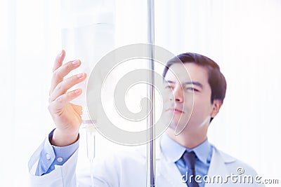 Doctor take care or look after patient by himself. Doctor checking Intravenous drip, I.V. tube saline fluid bag for cure patient Stock Photo