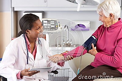 Doctor Taking Senior Female Patient's Blood Pressure Stock Photo