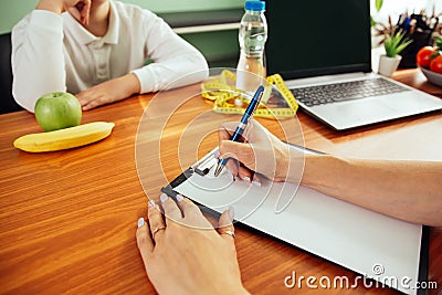 Doctor talking with child and writing diet plan. Childhood obesity Stock Photo