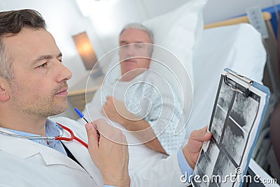 Doctor talking to senior male patient in hospital bed Stock Photo