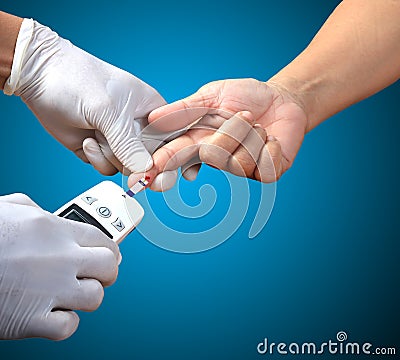 Doctor testing a patients glucose level after pricking his finger to draw a drop of blood and then using a digital glucometer Stock Photo