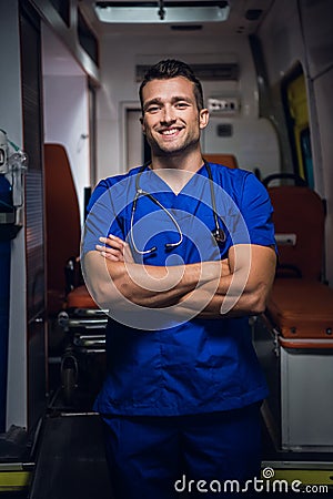 Doctor in uniform stands and looks at the camera smiling in the ambulance car Stock Photo