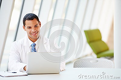 Doctor Using Laptop Sitting At Desk In Modern Hospital Stock Photo