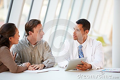 Doctor Using Tablet Computer Discussing Treatment With Patients Stock Photo