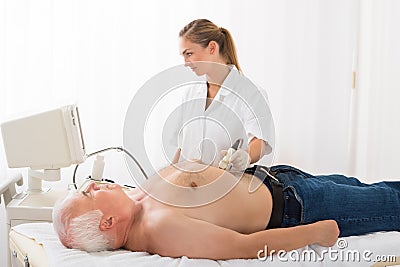 Doctor Using Ultrasound Scan On Abdomen Of Male Patient Stock Photo