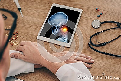 Doctor watching a digital tablet with x-ray of skull with pain in the neck. Migraine headache or trauma concept Stock Photo