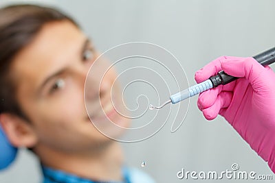 Doctor wearing pink gloves is holding ultrasonic dental scaler w Stock Photo