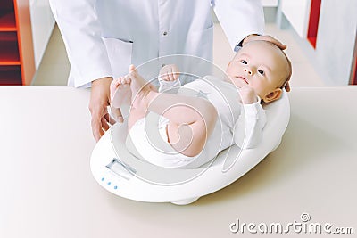 Doctor weighting cute baby at home Stock Photo