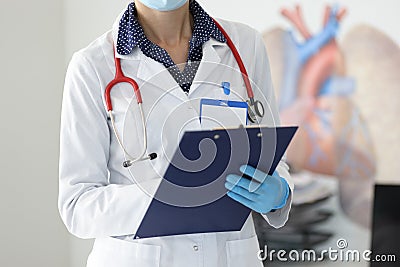 Doctor in white coat hold folder and write in office. Stock Photo