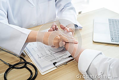 Doctor in white coat taking and checking the patient`s wrist pulse during the examination diagnosis in the hospital clinic Stock Photo