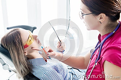 Doctor. Woman. Dentist talking to a young patient sitting on the dentist`s chair in the medical office. Shows in the Stock Photo