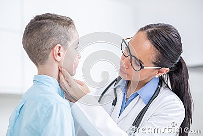 Doctor woman examining tonsils of young boy in medical office Stock Photo