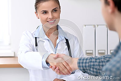 Doctor woman smiling while shaking hands with her male patient. Medicine and trust concept Stock Photo