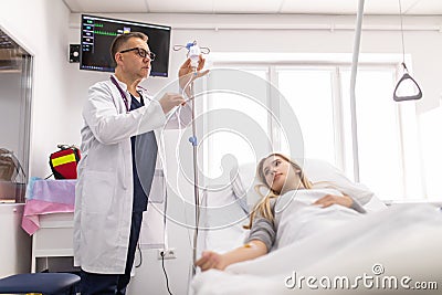 Doctor working, checking Intravenous drip, I.V. tube saline fluid bag for cure patient in hospital room. Handsome professional Stock Photo