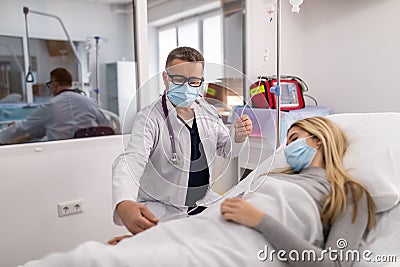 Doctor working, checking Intravenous drip, I.V. tube saline fluid bag for cure patient in hospital room. Handsome professional Stock Photo