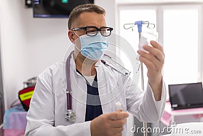 Doctor working, checking Intravenous drip, I.V. tube saline fluid bag for cure patient in hospital room. Handsome professional Stock Photo