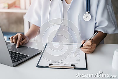 Doctor working on laptop computer and tablet and medical stethoscope on clipboard on desk, electronics medical record system EMRs Stock Photo