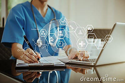 Doctor working on laptop computer, writing prescription clipboard with record information paper folders on desk in clinic, Stock Photo