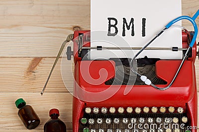 doctor workplace with blue stethoscope, pills, red typewriter with text BMI Body mass index Stock Photo