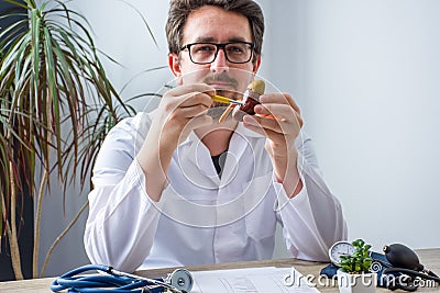 Doctor at workplace in office during appointment looks into camera, shows patient anatomic model of kidney and adrenal with focus Stock Photo