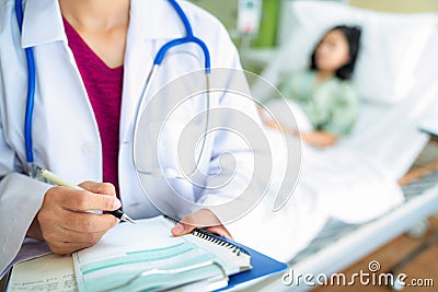 Doctor write a report after visit a patient on the bed in hospital Stock Photo