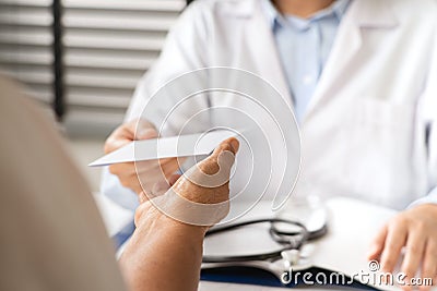 Doctor writing diagnosis and giving a medical prescription to senior women Patient Stock Photo