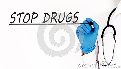 Doctor writing word STOP DRUGS Medical concept on white background Stock Photo