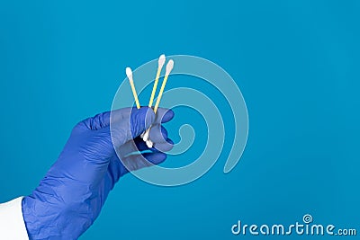 Doctors hand in a glove holds a plastic cotton swabs on a blue background with copy space Stock Photo