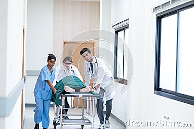 Doctors, Nurses, and Paramedics pushing stretcher gurney bed with seriously injured patient towards the operating room. Stock Photo