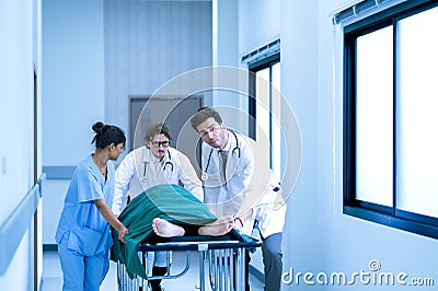 Doctors, Nurses, and Paramedics pushing stretcher gurney bed with seriously injured patient towards the operating room. Stock Photo