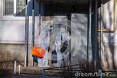 Doctors in protective suits at the door of an apartment building. coronavirus epidemic Editorial Stock Photo