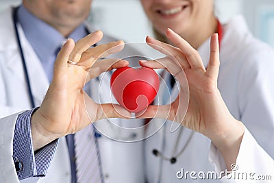 Doctors in white coats hold heart, focus on heart. Stock Photo