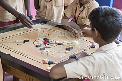 Documentary editorial image. Children playing carrom at the table. the concept of childhood and board games, brain development and Editorial Stock Photo