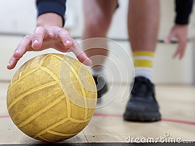 Dodgeball player picking up a yellow dodge ball Stock Photo