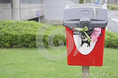 Dog poo waste only sign on red bin over flowing too many doggy bags falling out in public park encouraging owners pick up afterwa Stock Photo