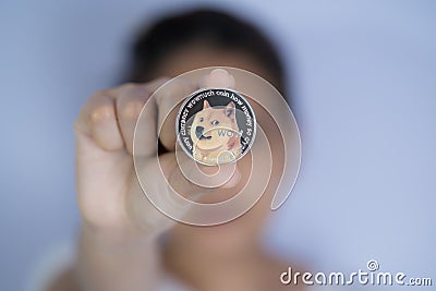 Dogecoin DOGE included with Cryptocurrency on hand working asian women holding coin in front face Filed and put and give to me. Editorial Stock Photo