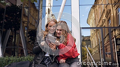 Dois amigos das mulheres que usam a tabuleta digital no ar livre Namoradas de sorriso que olham sobre fotos no dispositivo da tab video estoque Dois amigos das mulheres que usam a tabuleta digital no ar livre Namoradas de sorriso que olham sobre fotos no dispositivo da tab video estoque