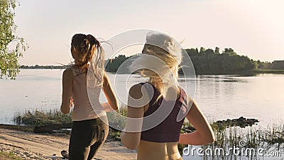 Dois corredores fêmeas bonitos novos que movimentam-se no parque perto do rio, aptidão modelam o corredor, fundo bonito da nature video estoque Dois corredores fêmeas bonitos novos que movimentam-se no parque perto do rio, aptidão modelam o corredor, fundo bonito da nature video estoque