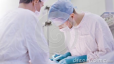 Dois doutores seguros novos que vestem a máscara e o uniforme do chapéu que executam o baixo ângulo da operação junto video estoque Dois doutores seguros novos que vestem a máscara e o uniforme do chapéu que executam o baixo ângulo da operação junto video estoque