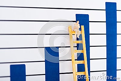 Doll character on ladder near blue graphs at background Stock Photo