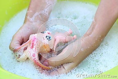 Doll in children`s hands in soapy water, close-up, top view-the concept of children`s outdoor games on a summer day Stock Photo