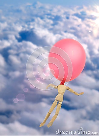 Doll made of wood with balloon in the head flies through the sky Stock Photo